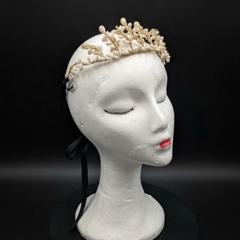 Tiara de novia antigua de cera y azahar sobre maniqu&iacute; con fondo negro, &eacute;poca victoriana circa 1900.