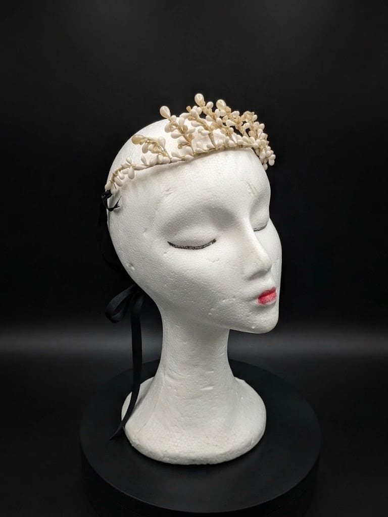 Tiara de novia antigua de cera y azahar sobre maniquí con fondo negro, época victoriana circa 1900.